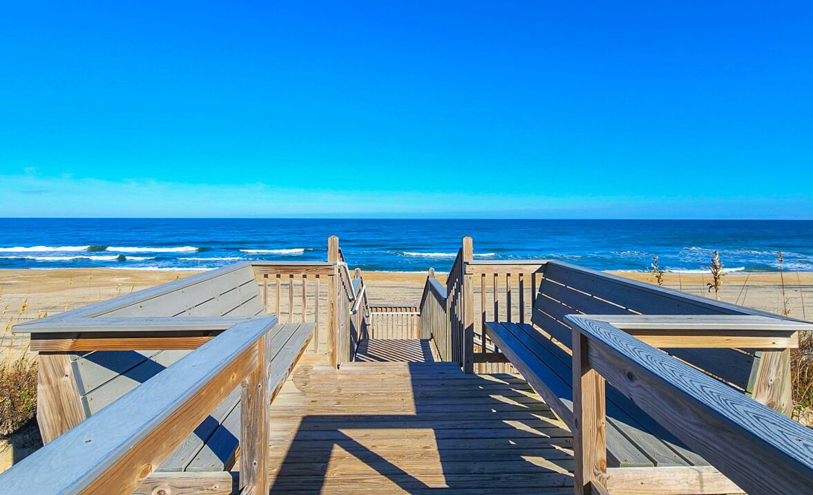 A wooden boardwalk leading to the beach with a clear view of the ocean.