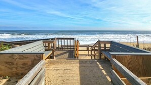 Ein hölzerner Steg führt zum Strand, mit einer Holzbrüstung und einem Tor.