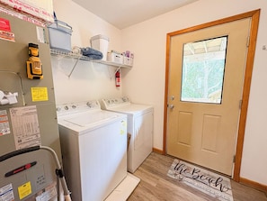 A laundry room with two washing machines, a dryer, and a shelf with laundry supplies. - House N Duck - Located in the heart of Duck, this 5 BR home is a pleasant walk away from the beach! (Duck)