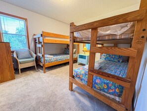 A room with bunk beds, a chair, and a nightstand.