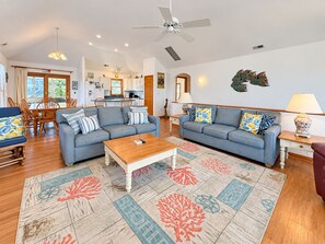 A spacious living room with two sofas, a coffee table, and a dining area with chairs and a table. - House N Duck - Located in the heart of Duck, this 5 BR home is a pleasant walk away from the beach! (Duck)