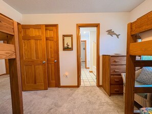 A hallway with wooden doors, a framed picture, and a bunk bed.