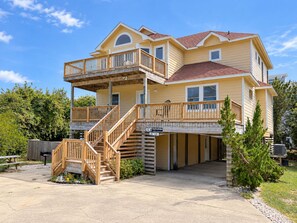 A two-story building with a balcony on the upper level and a covered entrance. - House N Duck - Located in the heart of Duck, this 5 BR home is a pleasant walk away from the beach! (Duck)