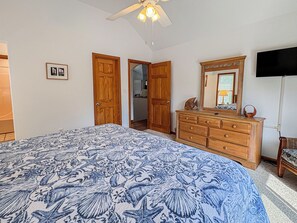 A bedroom with a large bed, wooden wardrobe, dresser, and a television. - House N Duck - Located in the heart of Duck, this 5 BR home is a pleasant walk away from the beach! (Duck)
