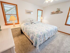 A bedroom with a bed, nightstands, a lamp, a picture frame, and a wall decoration. - House N Duck - Located in the heart of Duck, this 5 BR home is a pleasant walk away from the beach! (Duck)
