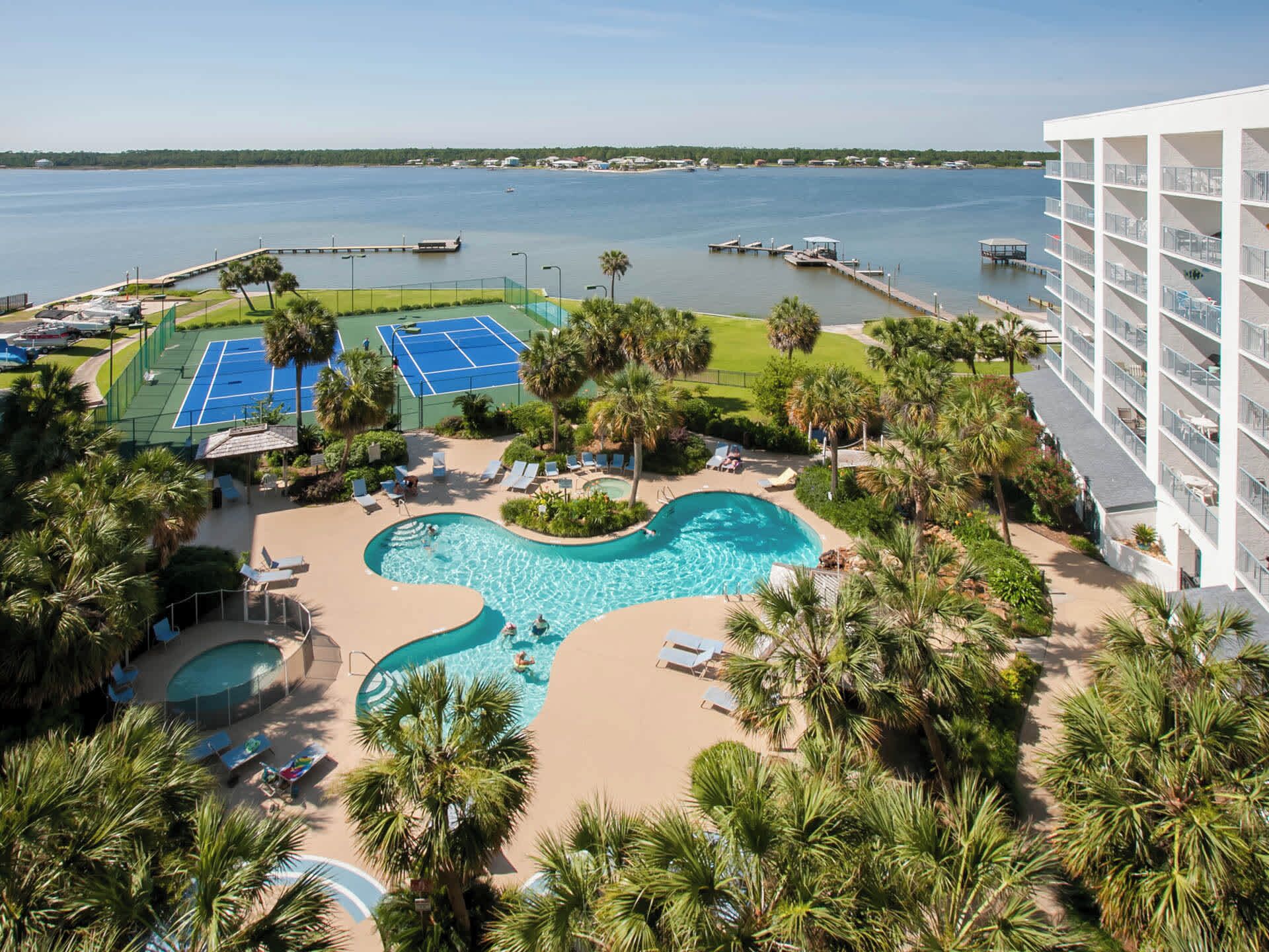 Un complexe hôtelier doté d’une piscine, de courts de tennis et offrant une vue sur l’eau.