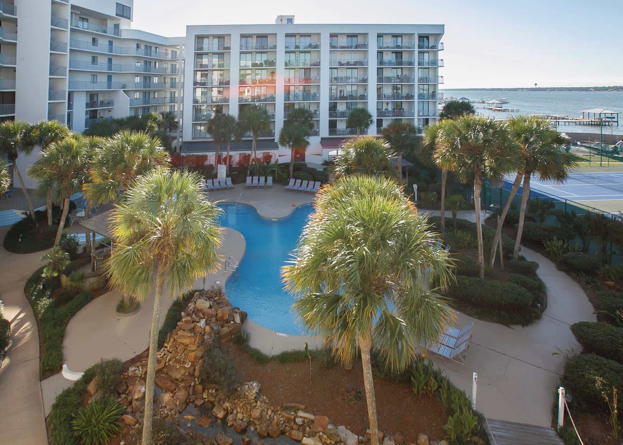 Ein Hotel mit Pool, umgeben von Palmen und Blick auf das Meer.