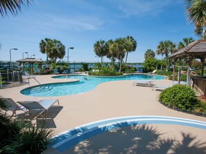 A pool area with lounge chairs, palm trees, and a gazebo.