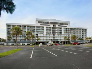 A multi-story hotel with a modern architectural design, featuring a parking lot in front.