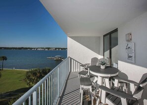 A balcony with a view of the water, a table with chairs, and a sign with a love quote.