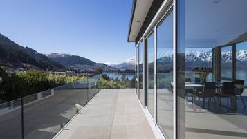 A modern building with large glass windows offering a view of a lake and mountains.
