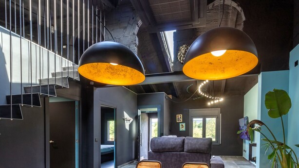 Un intérieur moderne avec une table à manger en bois, des murs sombres et deux grandes lampes suspendues.