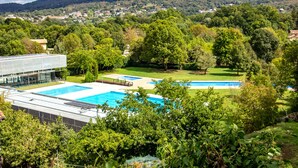Un complexe hôtelier doté de plusieurs piscines, entouré d’une végétation luxuriante et offrant une vue sur une ville située au loin.