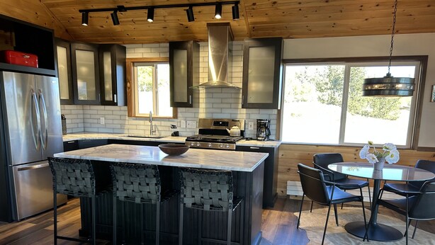 A modern kitchen with a central island, stainless steel appliances, and a dining area with a round table and chairs.