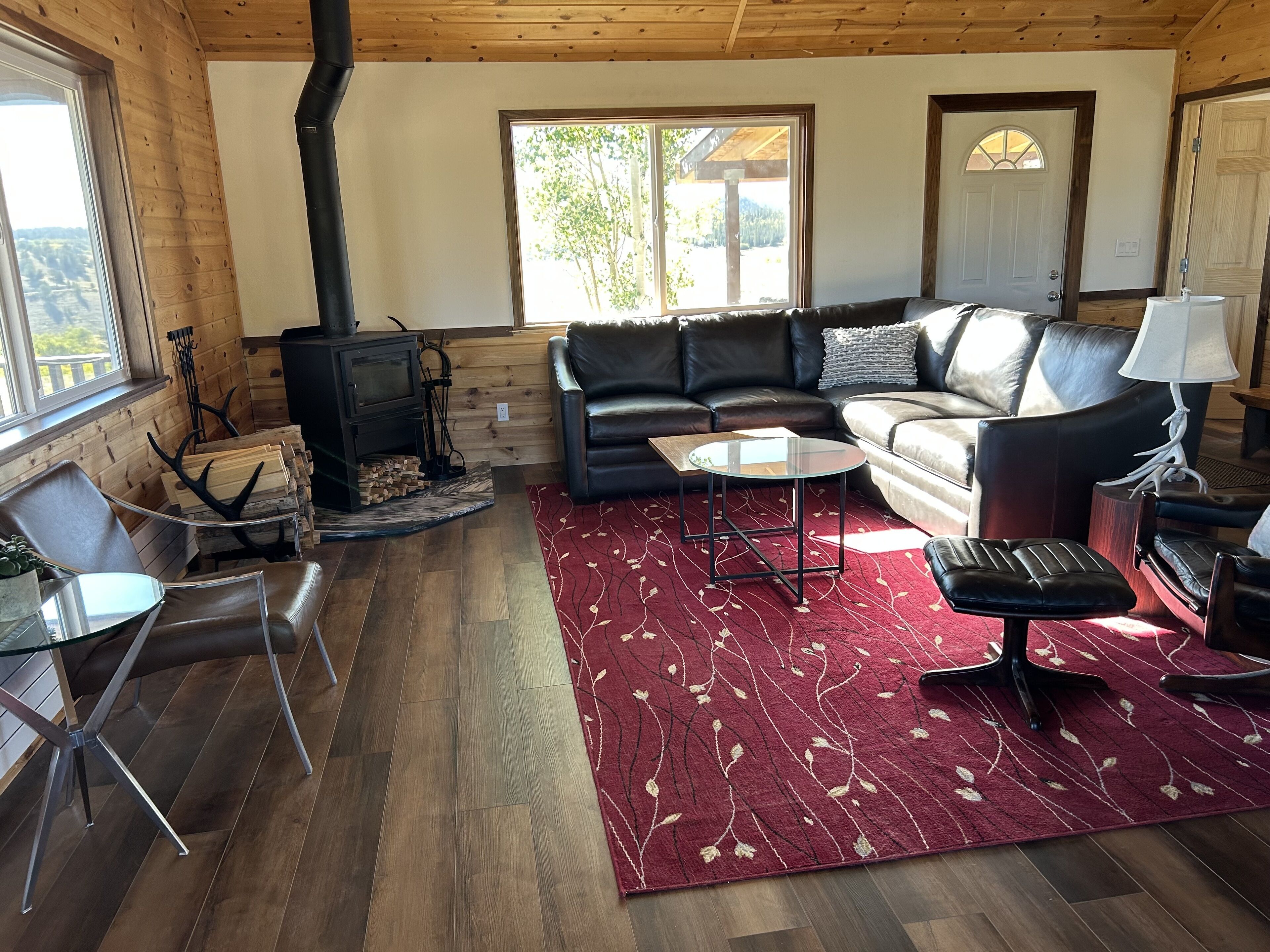 A cozy living room with a fireplace, leather sofa, and a red patterned rug.