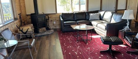 A cozy living room with a fireplace, leather sofa, and a red patterned rug.