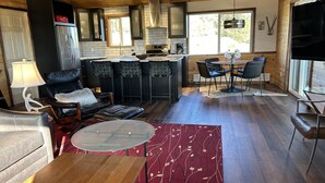 A modern kitchen with a central island, bar seating, and a dining area with a large window.