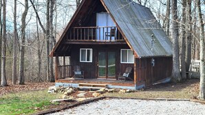 Eine Holzhütte mit Balkon und Veranda, auf der zwei Stühle stehen.