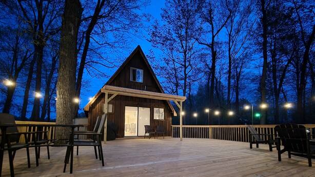 Eine Holzhütte mit einer Terrasse, umgeben von Bäumen.
