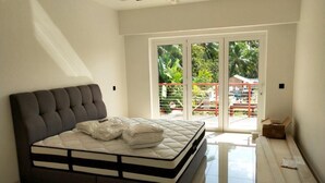 Een slaapkamer met een groot bed, een plafondventilator en uitzicht op een balkon met buitenmeubilair.
