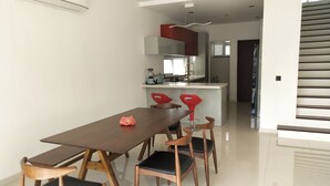 Een moderne keuken met een centraal eiland, rode barkrukken en een eettafel met houten stoelen.