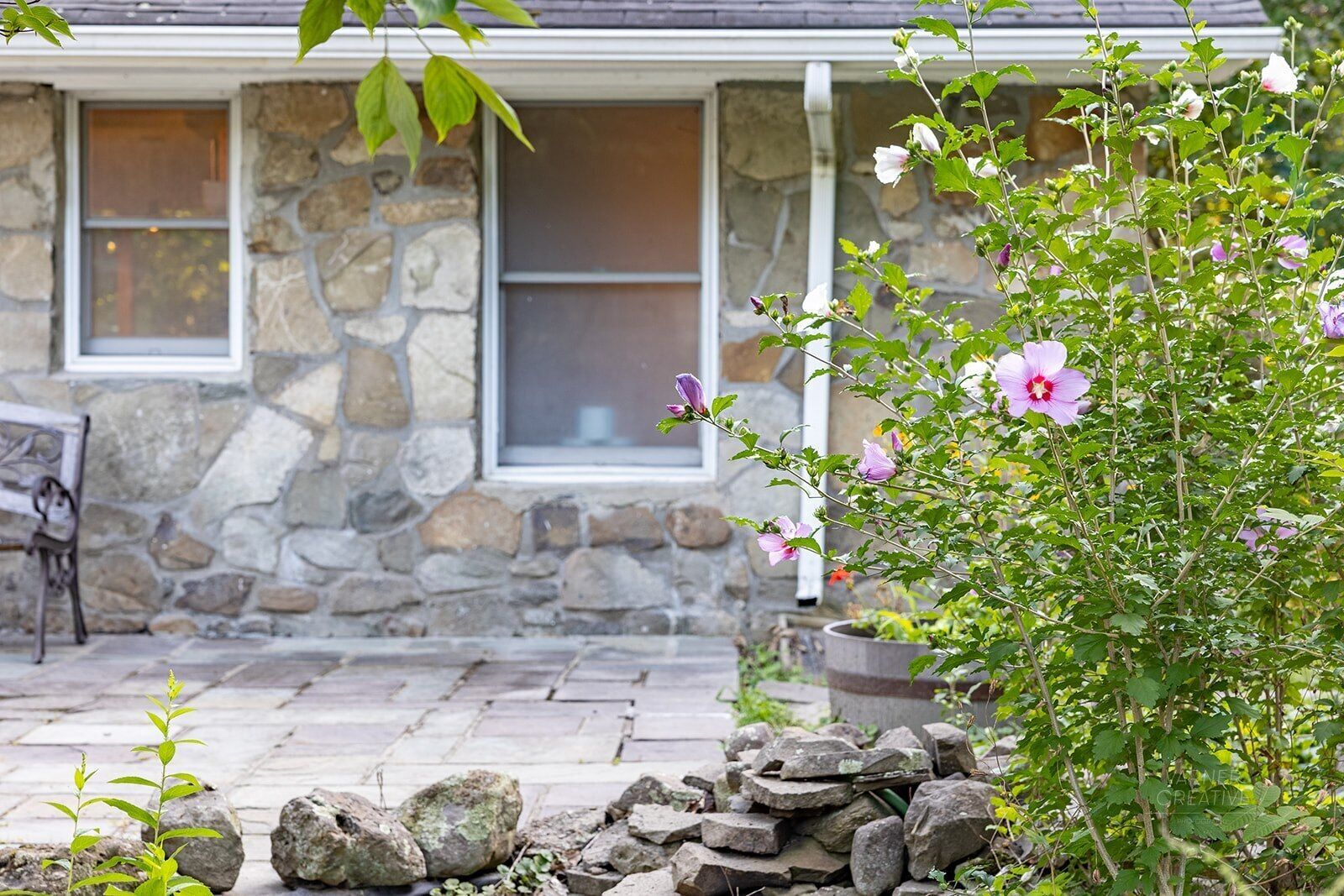 Una casa de piedra con fachada de piedra, una ventana y una maceta con flores.