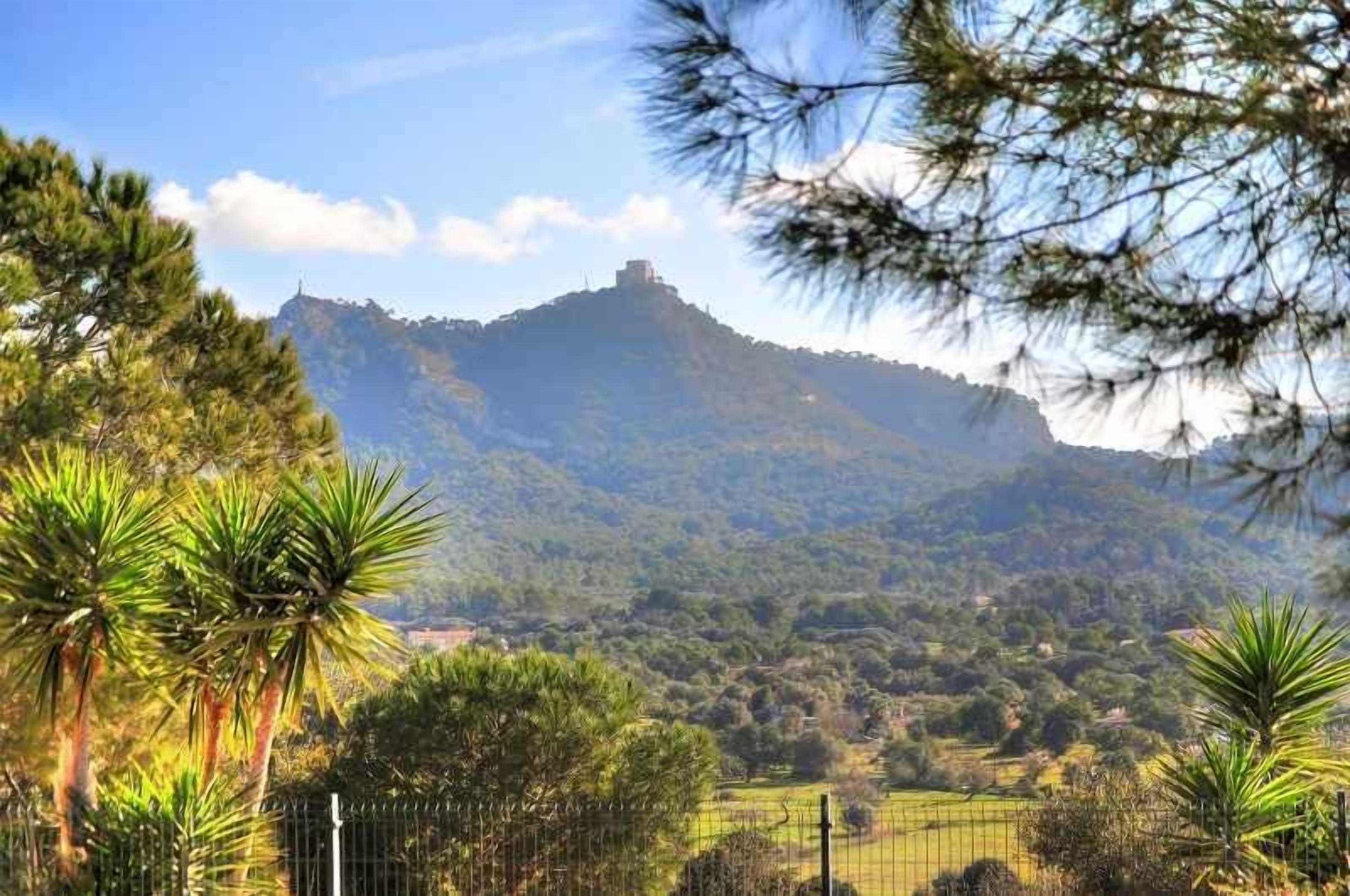 Eine gebirgige Landschaft mit einem markanten Hügel und einem Gebäude auf der Spitze.
