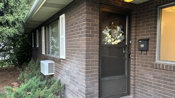 A brick house with a dark front door, a small porch, and a mailbox.