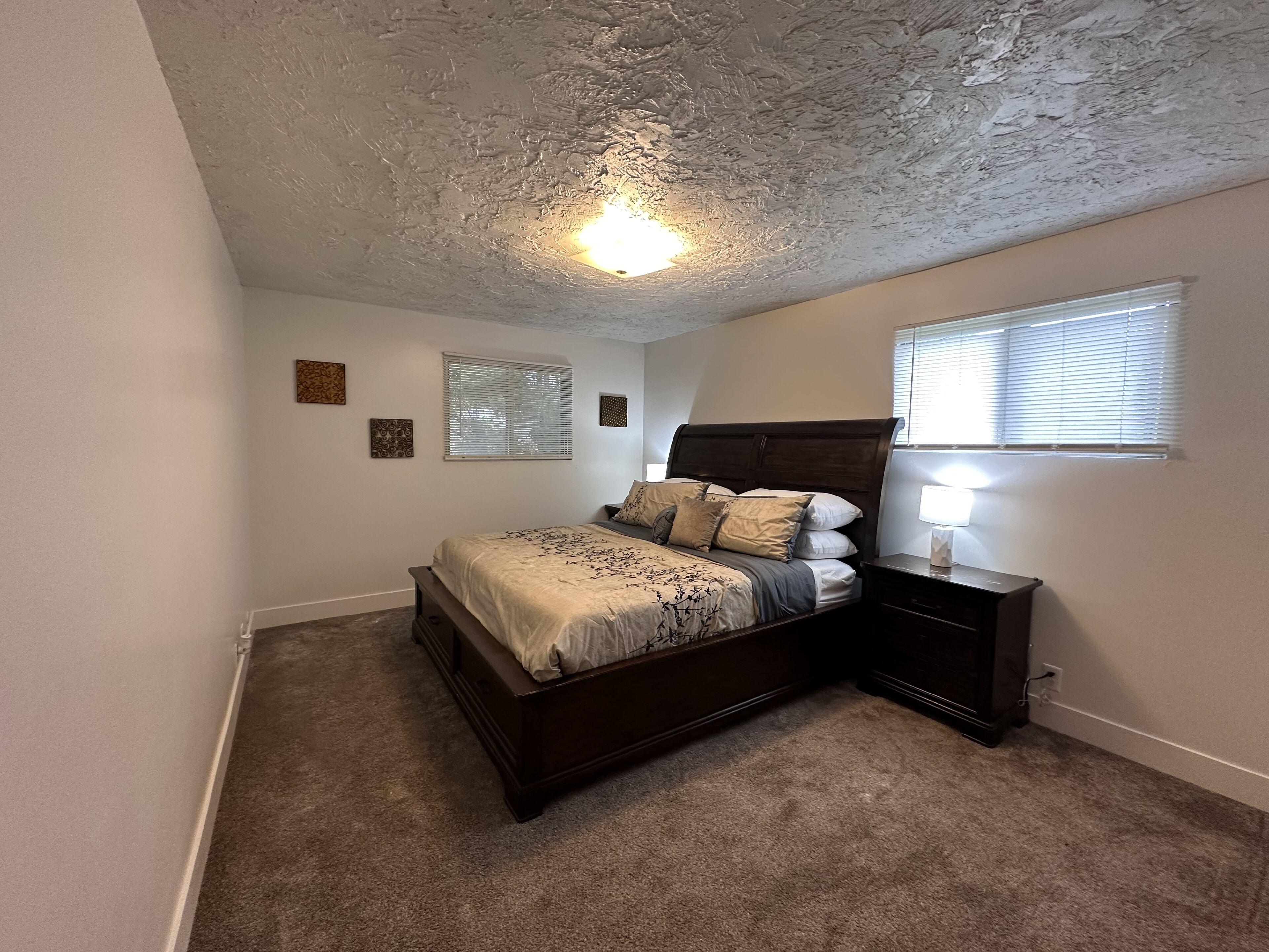 A bedroom with a bed, nightstand, and wall-mounted lamp.