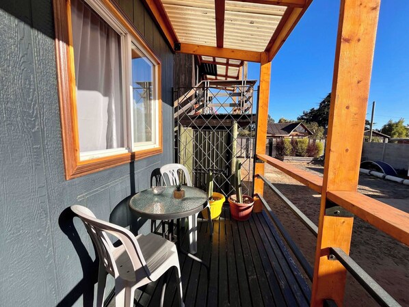 Un espacio al aire libre cubierto con mesa y sillas, una ventana y vistas a una zona residencial.