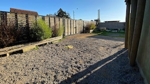 Ein befestigter Weg aus Kies führt zu einem Holzzaun mit einem Metalltor.