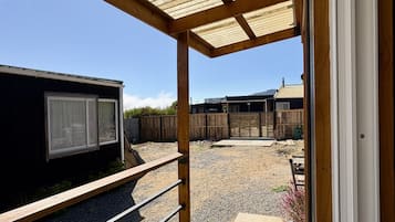 A wooden deck with a pergola overhead, a gravel area, and a fenced yard.