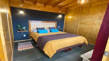 A wooden-paneled room with a bed, a small table, and a hanging light fixture.