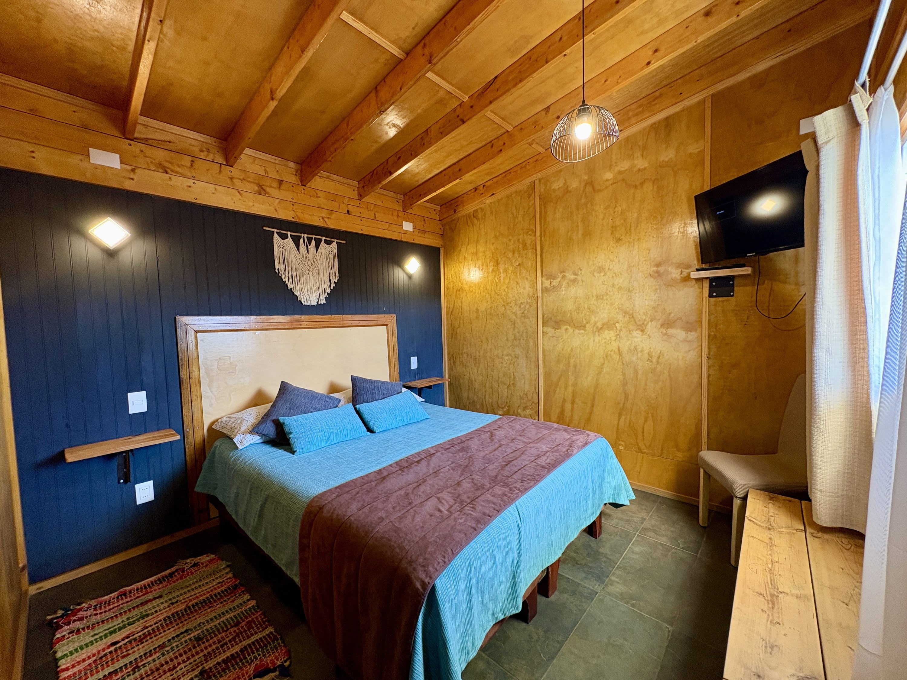 A wooden-paneled room with a bed, a television, and a bench.