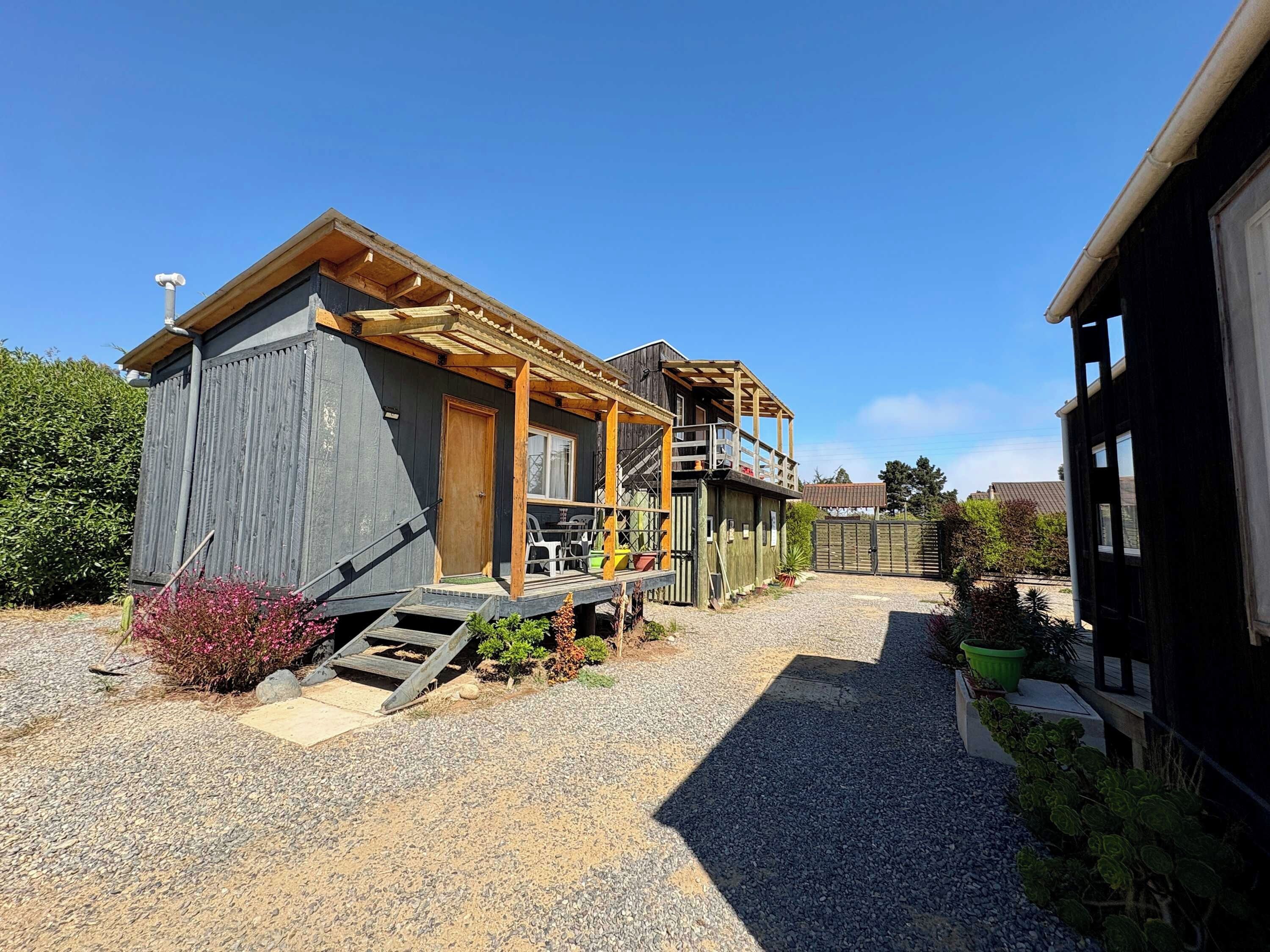Une cabane rustique dotée d’une terrasse en bois, d’un escalier menant à un porche et d’une cour clôturée.