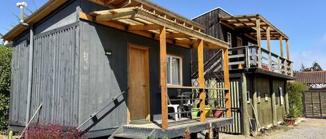 Una casa de madera con un porche, una escalera y un pequeño jardín.