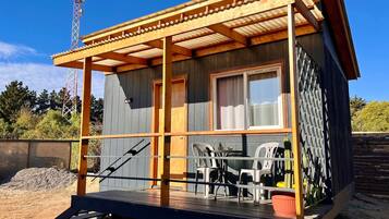 A wooden cabin with a porch, a table, and chairs.