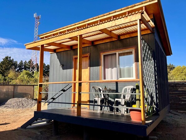 Una cabaña de madera con un porche, una mesa y sillas.