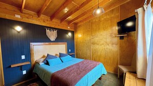 Una habitación con paneles de madera, una cama, un televisor y un banco.