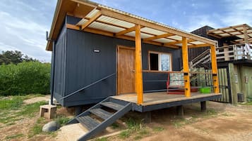 A small, single-story cabin with a wooden deck and a metal roof.