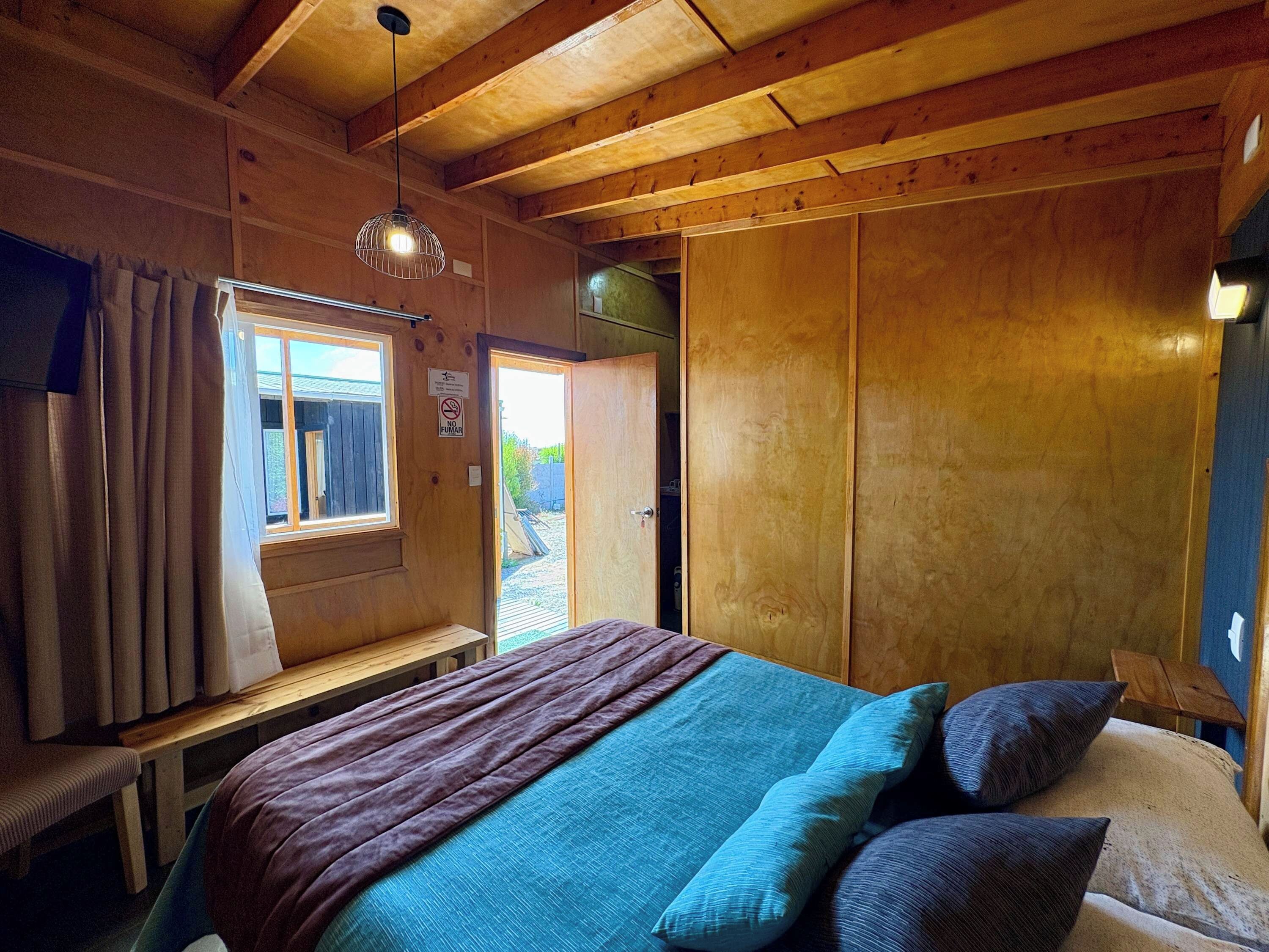 Un intérieur en bois avec un lit, un banc et une fenêtre.