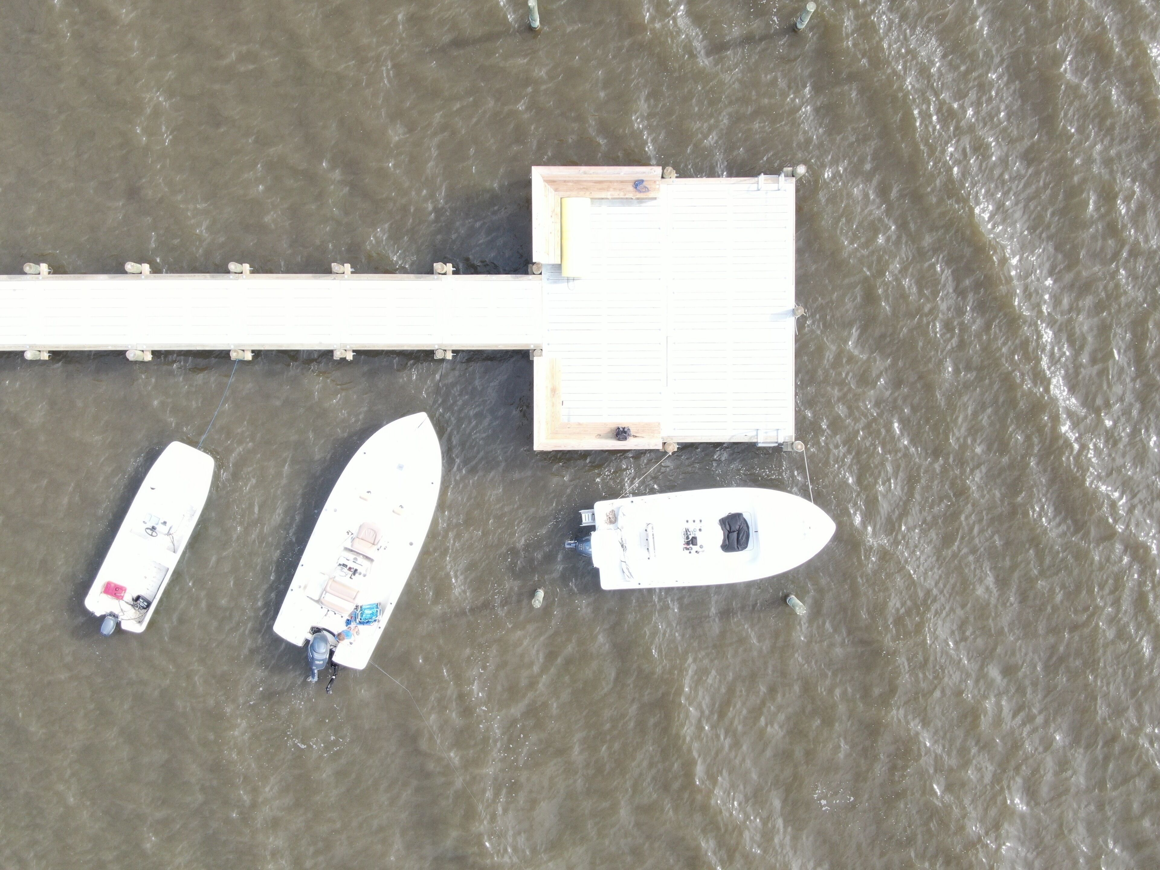 An aerial view of a dock with three boats moored alongside.
