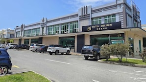 A modern hotel with a sign reading "HOTEL MELIDEN" and a parking lot with several cars. - Hotel Meliden (Sandakan)