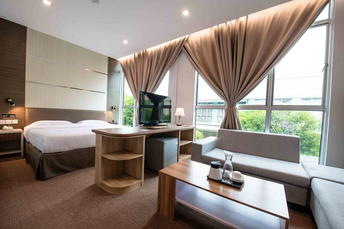 Una habitación de hotel moderna con cama, escritorio, sofá y televisión.