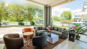 A modern hotel lobby with a large seating area, a coffee table, and a view of the street and greenery outside. - Hotel Meliden (Sandakan)