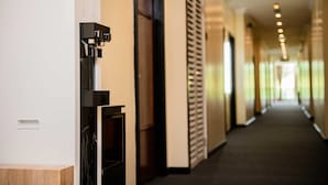 A hotel corridor with a coffee machine, a door, and a ventilation system. - Hotel Meliden (Sandakan)