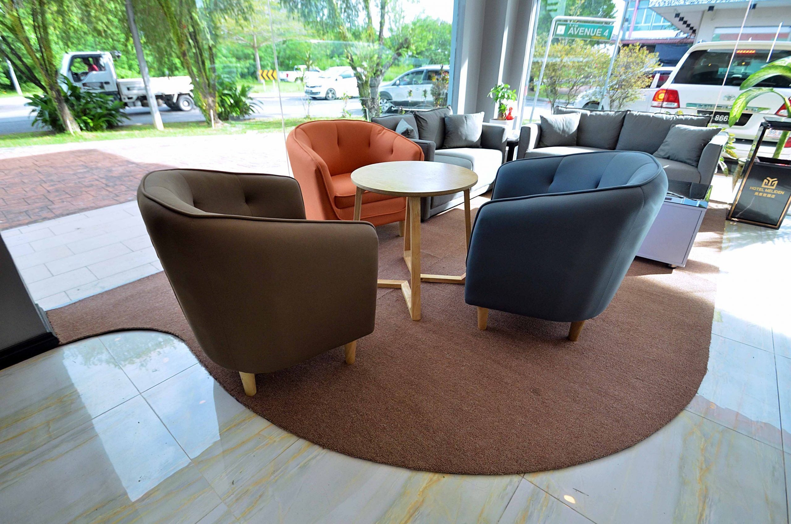 A modern hotel lobby with a seating area featuring sofas and armchairs, a small round table, and a carpeted floor.