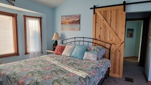 A bedroom with a bed, a wooden barn door, a motivational quote, and a window with curtains. - Lakeside Paradise with Priceless Views (Toledo)
