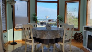 A dining area with a round table, white chairs, and a view of boats and water through large windows. - Lakeside Paradise with Priceless Views (Toledo)