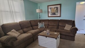 A living room with a brown sectional sofa, a small white table, and a framed picture on the wall. - Lakeside Paradise with Priceless Views (Toledo)